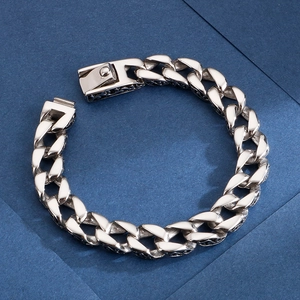 Polished silver stainless steel Cuban link bracelet with engraved pattern on a blue surface