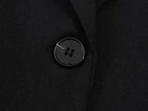 Macro view of black twill fabric texture and classic four-hole button on the blazer