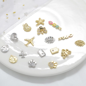 Detailed assortment of gold and silver charms including starfish, bees, and planes in a bowl