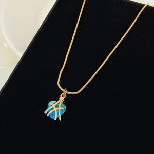Detalle de collar de corazón dorado con cristal azul sobre terciopelo negro