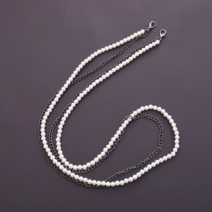 Detail of dual-layer strap with white pearls and dark metal chain featuring lobster clasps