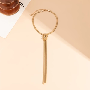 Detail einer goldenen Schlangenkette in Y-Form mit einem Knoten und langen Quasten
