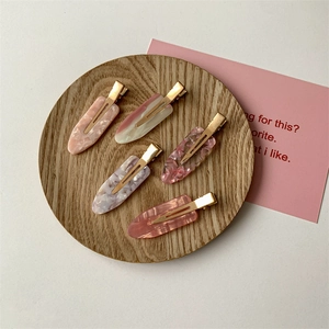 Five colorful marble pattern seamless hair clips displayed on a round wooden tray
