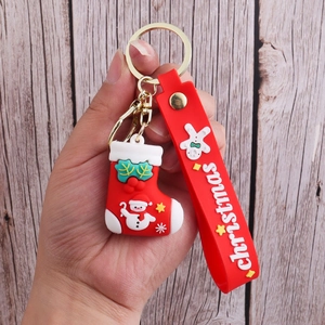 Close-up of a red PVC Christmas stocking keychain with metal ring on wood background