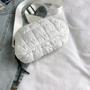 Macro shot of white quilted nylon fabric detail and adjustable strap on cross-body bag