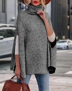 Dettaglio di un poncho grigio in maglia a collo alto che mostra la trama del tessuto all'aperto