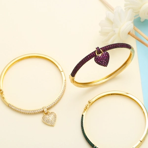 Detail of heart pendant bangles with micro-pave zircons in gold, red, and green finishes