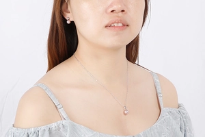 Detail of elegant silver necklace and earring set with pink pearl pendants on model