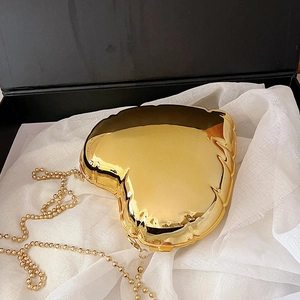 Golden heart-shaped evening clutch bag with bead chain inside an elegant gift box
