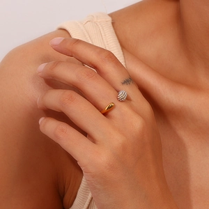 Minimalist open ring with a gold drop charm and a white beaded pearl on a woman's finger
