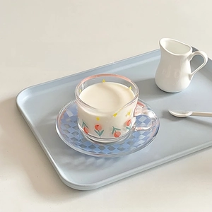 Detail shot of tulip flower glass cup and blue checkerboard saucer set for afternoon tea