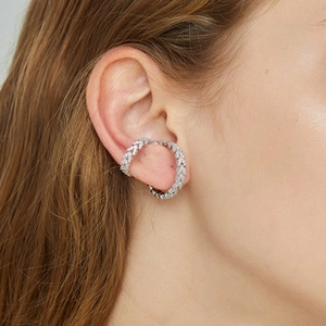 Close-up of a silver ear cuff with shimmering small diamonds worn on the ear cartilage