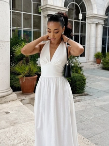 Detail of white cotton halter maxi dress featuring deep V-neck and cinched waistline