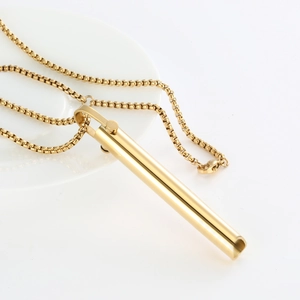Close-up of a golden cylindrical mindfulness pendant on a white ceramic plate