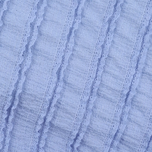 Close-up of light blue fabric featuring pleated texture and elegant lace trim details