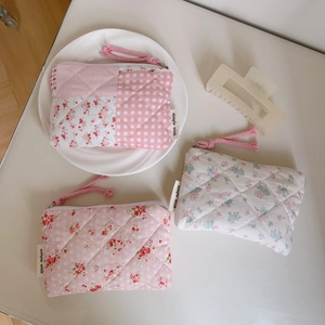Close-up of floral quilted cotton coin purses with pink zippers on a white desk
