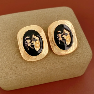 Detail of vintage oval stud earrings with black enamel and golden horse carriage motif