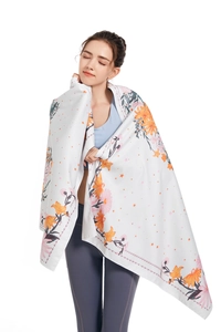 Detail of soft microfiber beach towel with vibrant orange floral and leaf print pattern
