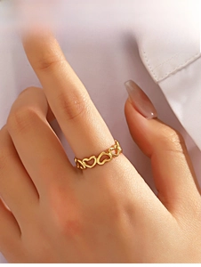 Detail of golden stainless steel ring featuring a continuous hollow heart pattern design