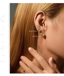 Detail showing 7mm and 8mm yellow round-cut silver stud earrings worn by a model