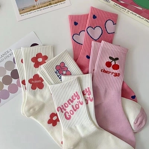 Dettaglio di calze in cotone rosa e bianco con dolci motivi a cuore e decorazioni floreali