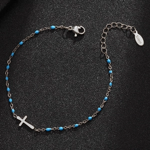 Detail showing silver stainless steel cross bracelet with blue beads on black surface