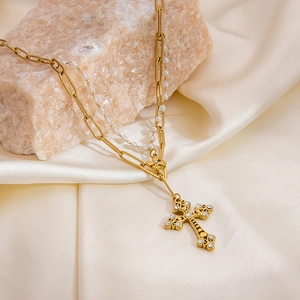 Détail d'un collier double épingle à nourrice doré avec perles et pendentif croix en zircon