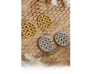 Detail of hollow woven link earrings in gold and silver finish with metallic texture
