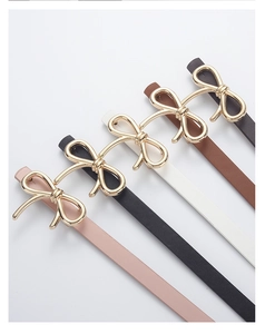 Detail of four colorful PU leather skinny belts featuring elegant gold bow buckles
