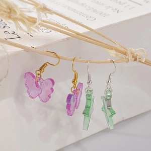 Detail of star and butterfly resin charms hanging on natural dry branches for DIY project