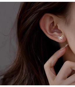 Macro detail of a colorful butterfly stud earring in s999 sterling silver on an ear