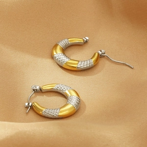 Close-up of two-tone U-shaped earrings with gold and silver snake skin texture