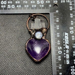 Detailed view of vintage bronze pendant with amethyst heart and white crystal points