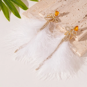 Vintage gold bow earrings with crystal tassels and fluffy white feathers on stone