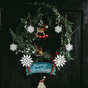 White Christmas snowflake hanging decorations with Merry Christmas sign on dark wooden door