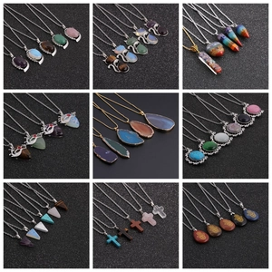 Various crystal teardrop and geometric stone pendants displayed on black texture