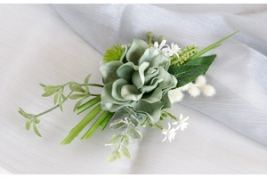 Sage green succulent boutonniere with eucalyptus and berries on white silk fabric