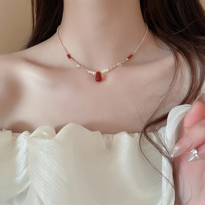 Detail of 18k gold-plated necklace with fresh water pearls and red teardrop pendant