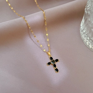 Close-up of gold cross pendant with black zircon stones on purple silk background