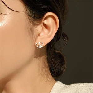 Macro side view of a twisted silver heart stud earring worn on a model's earlobe