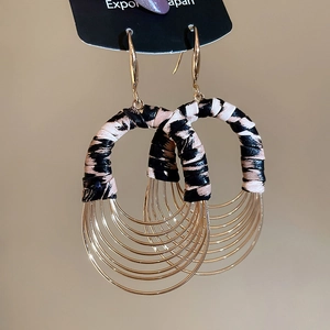 Macro shot of bohemian leopard print leather and multilayer gold hoop drop earrings