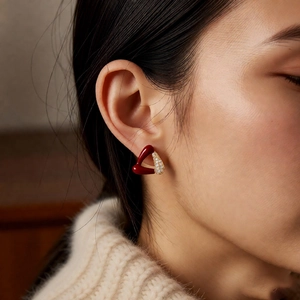 Gros plan de boucles d'oreilles triangulaires rouges élégantes dorées sur un mannequin