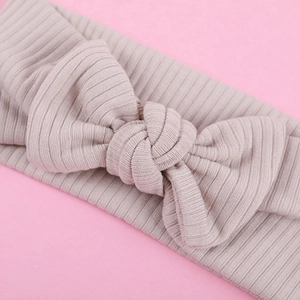 Detailed ribbed knit texture of baby headband with a soft mauve bow tie decoration