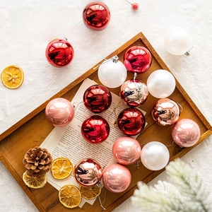 Red, white and rose gold Christmas ball ornaments set on a rustic wooden tray with pine cones