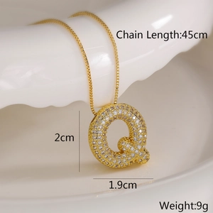 Detail showing gold letter Q pendant with crystals and dimensions on a white plate