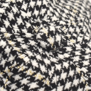 Makroaufnahme von Hahnentritt-Tweed mit metallischem Goldfaden und passendem Knopf
