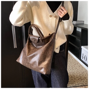 Detail van een grote bruine vintage tote tas met matte kunstlederen textuur en handvat