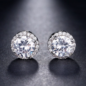 Macro view of round halo stud earrings featuring sparkling cubic zirconia in silver setting