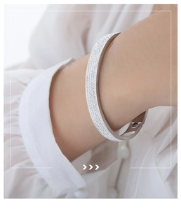 Detail of silver paved crystal bangle on a white shirt sleeve in elegant macro shot