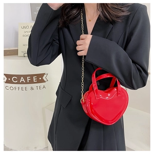 Red heart-shaped jelly bag with gold chain shown styled on a black professional blazer